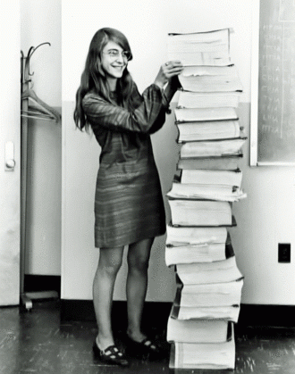 Margaret Hamilton debout à côté de la pile de listings du programme de vol d'Apollo 11, qu'elle a dirigé.